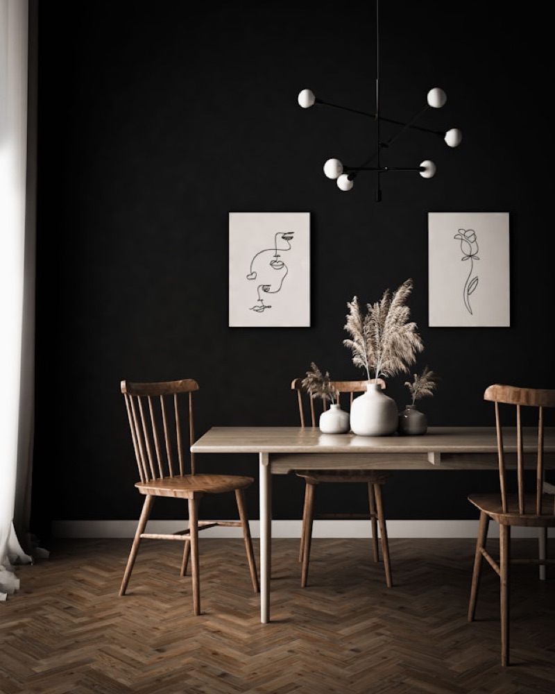 Styled dining room with dark walls, a wooden table, and a pampas-grass arrangement